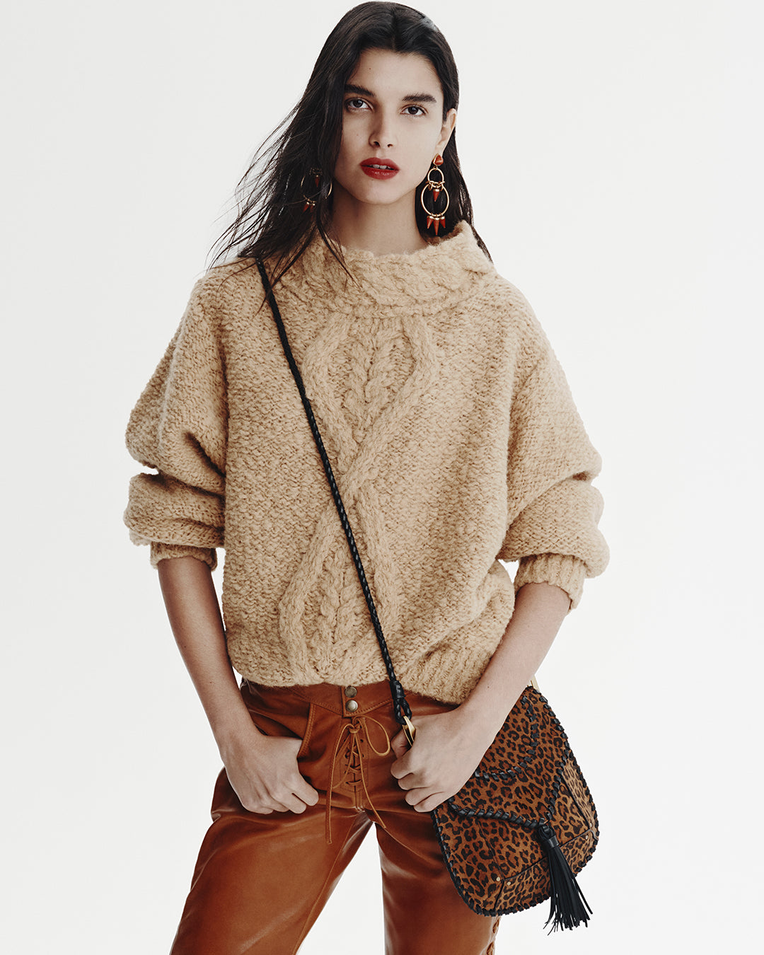 Model wears a beige jumper with orange leather pants.