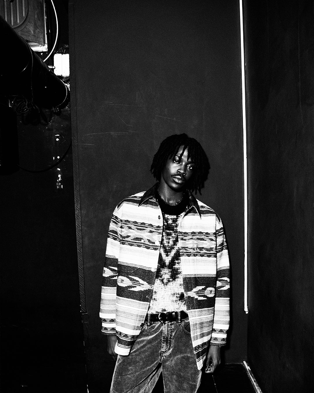 Men in a club wearing patterned jacket and jumper on a black and white images.