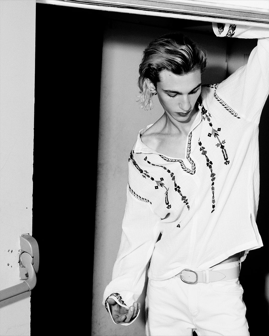 Men model with on arm up wearing on embroidered blouse.