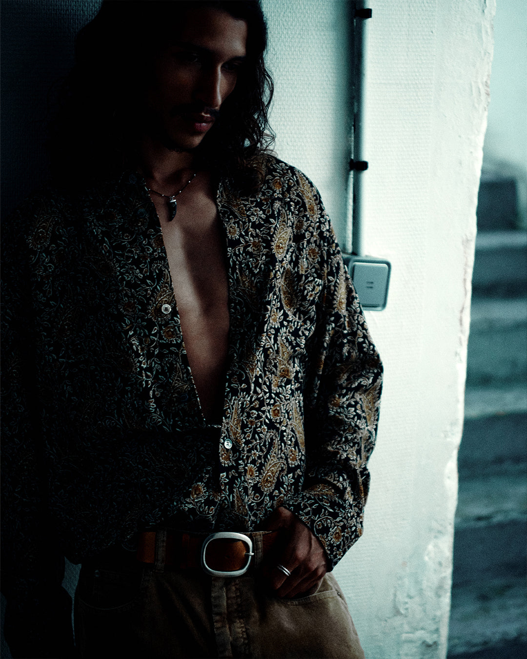 Men in a shadow wearing a floral patterned shirt.