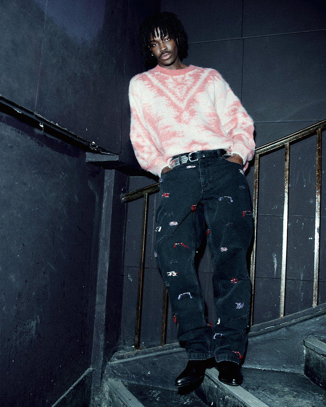 Pink jumper worn by a men model in the stairs.