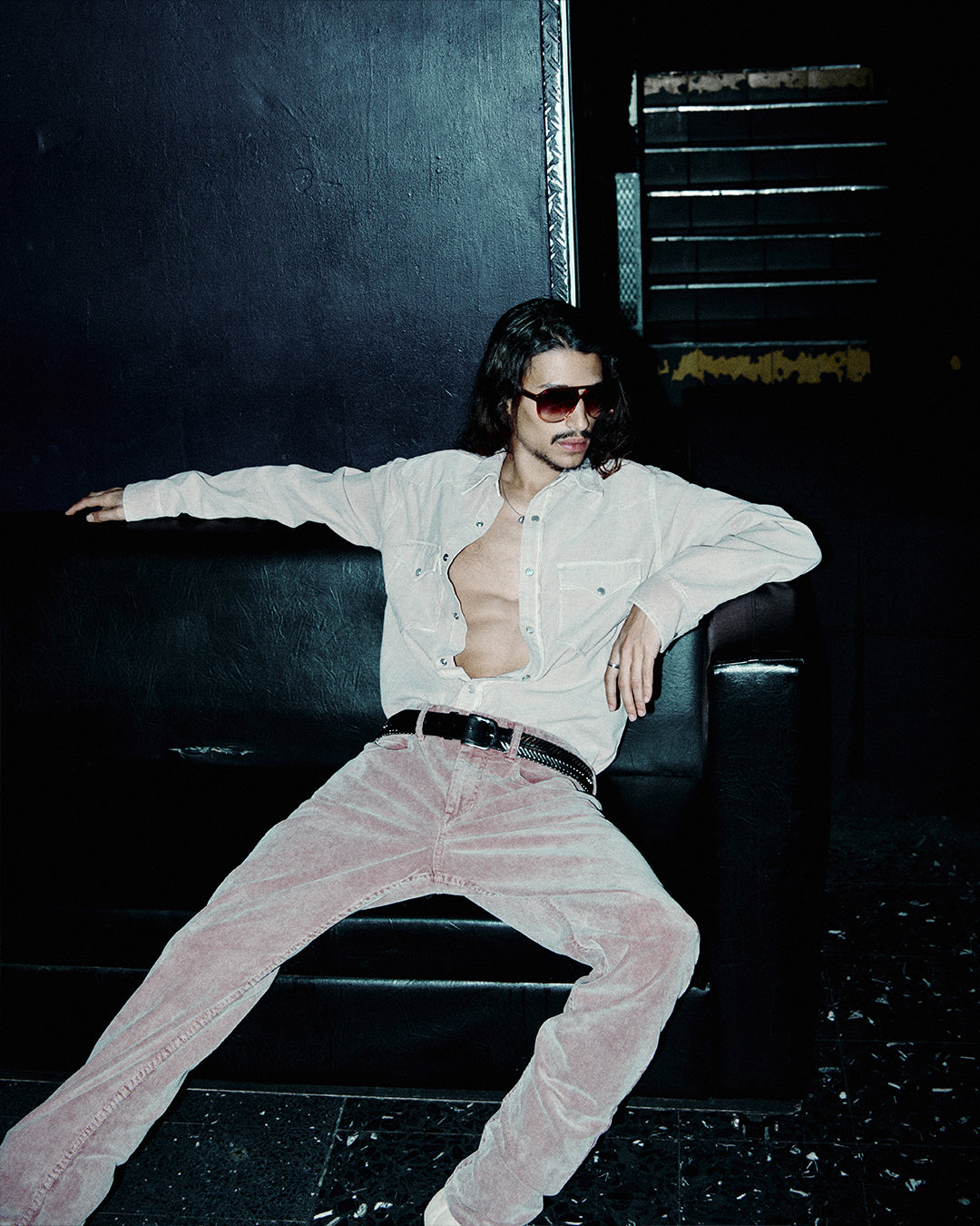 Men seats on the couch wearing pink matching outfit in denim.