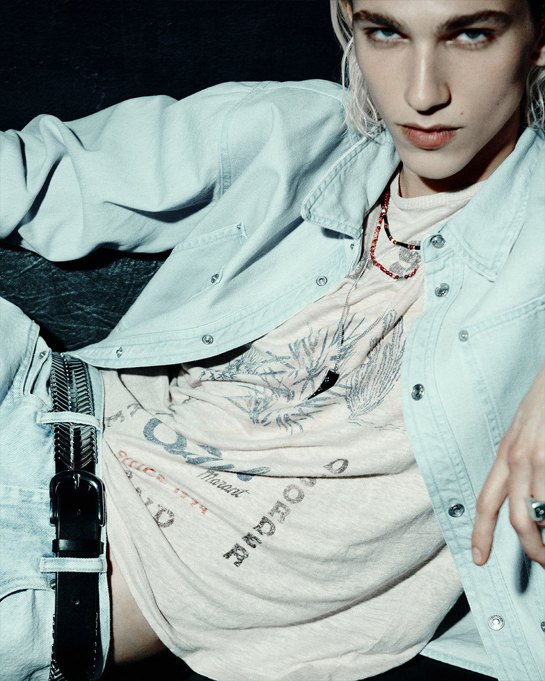 Zoom on the portrait of a men model wearing light blue denim jacket and printed t-shirt.