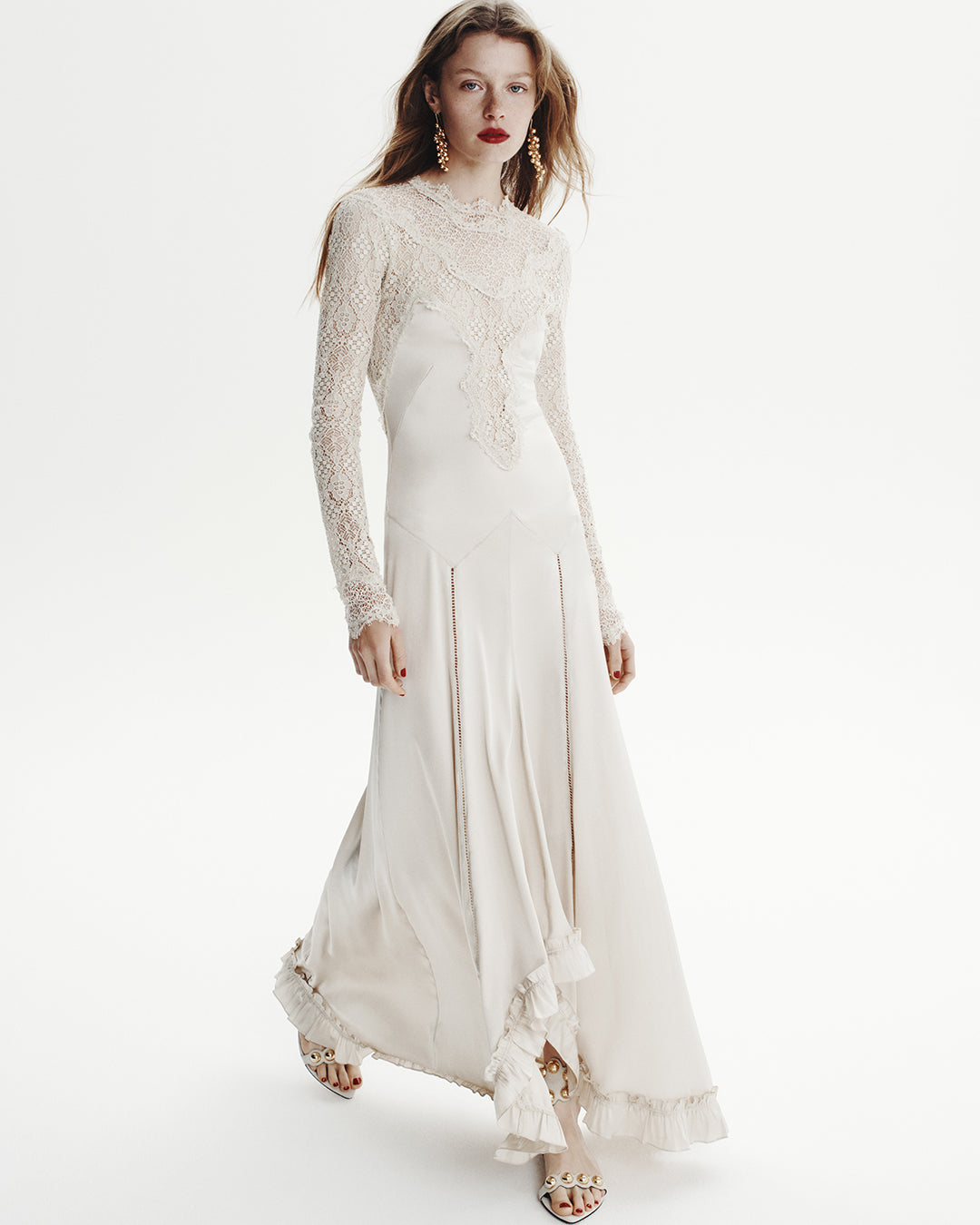 Model wears a long white dress with laces details on top.
