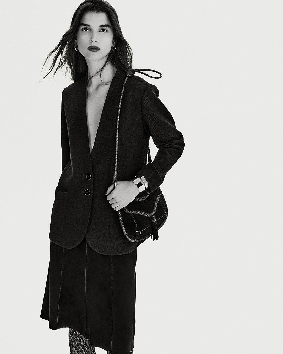 The image mood is black and white with the model wearing a blazer and the Anahi bag.