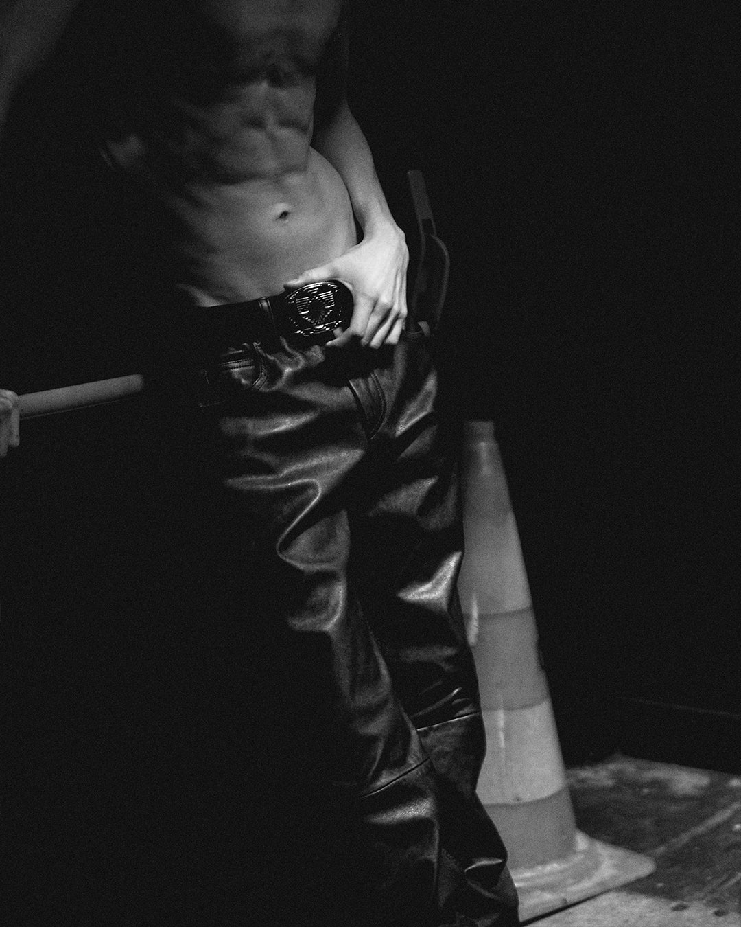 Bare-chested men model in a club wearing a leather pants.