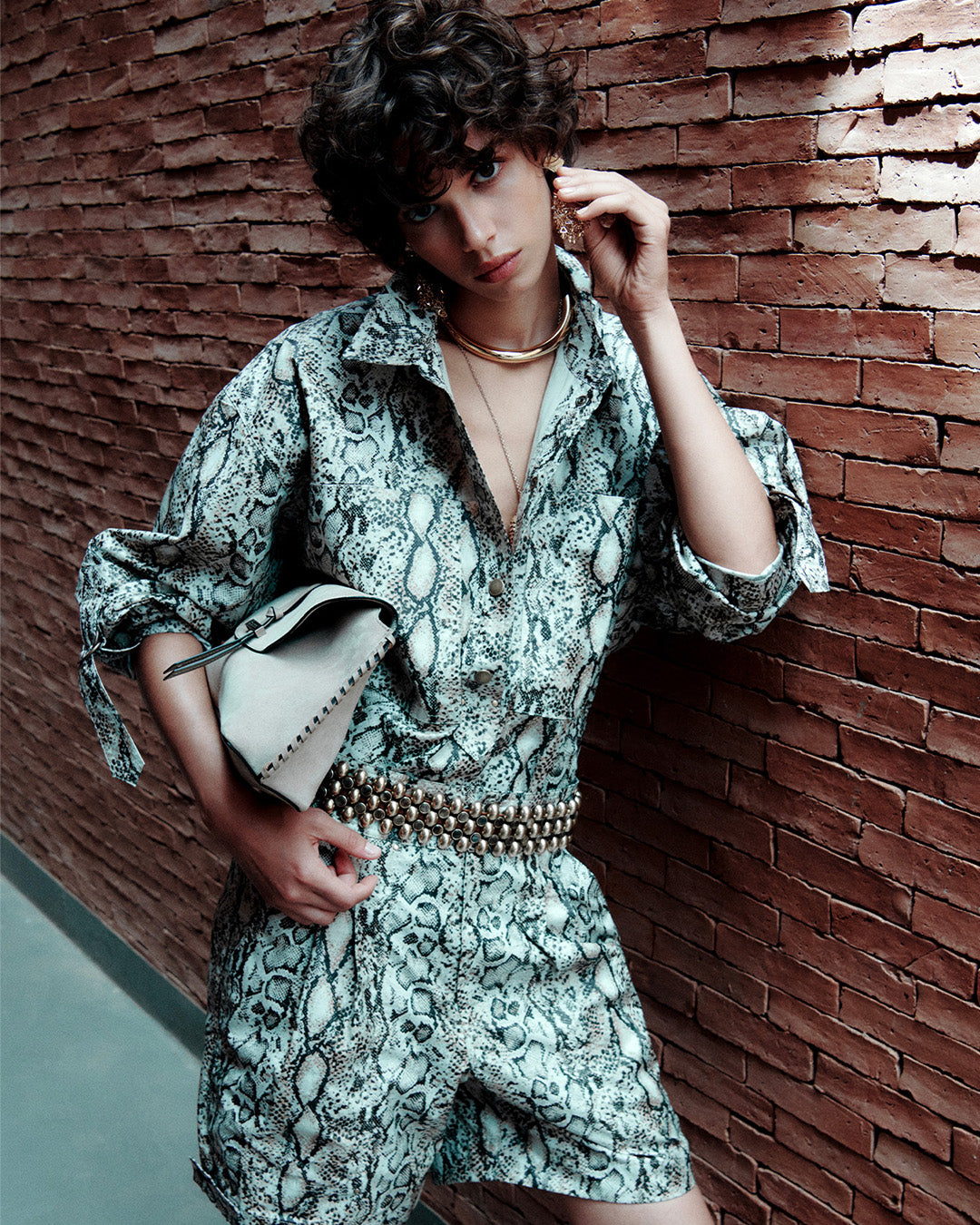 Feminine model, dressed in a python print shirt with matching shorts and varana belt