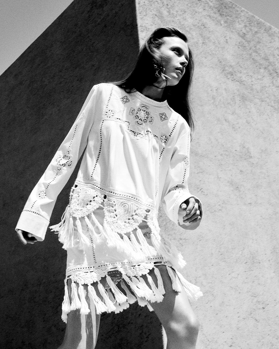 Feminine model wearing the Severine top in white macramé, the Sandra mini-skirt in white macramé and mijina earrings.