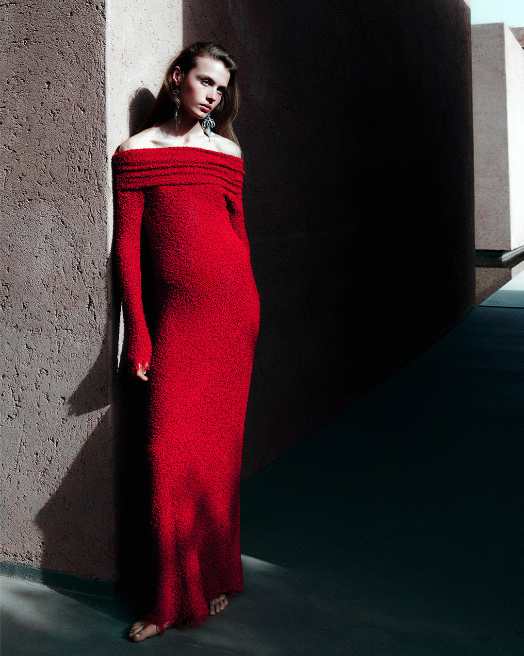 Feminine model, dressed in the Ormany long dress in red bouclé jersey and mijina earrings
