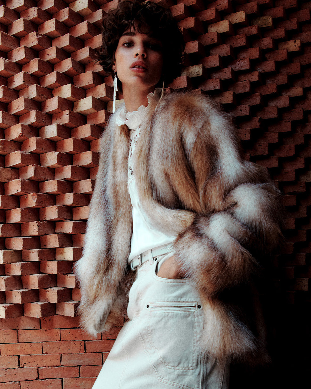 Feminine model, dressed with the Aglae fur-effect coat, the Seila flowing blouse with ecru lace and ruffles and the Britt midi skirt in ecru cut-out denim.