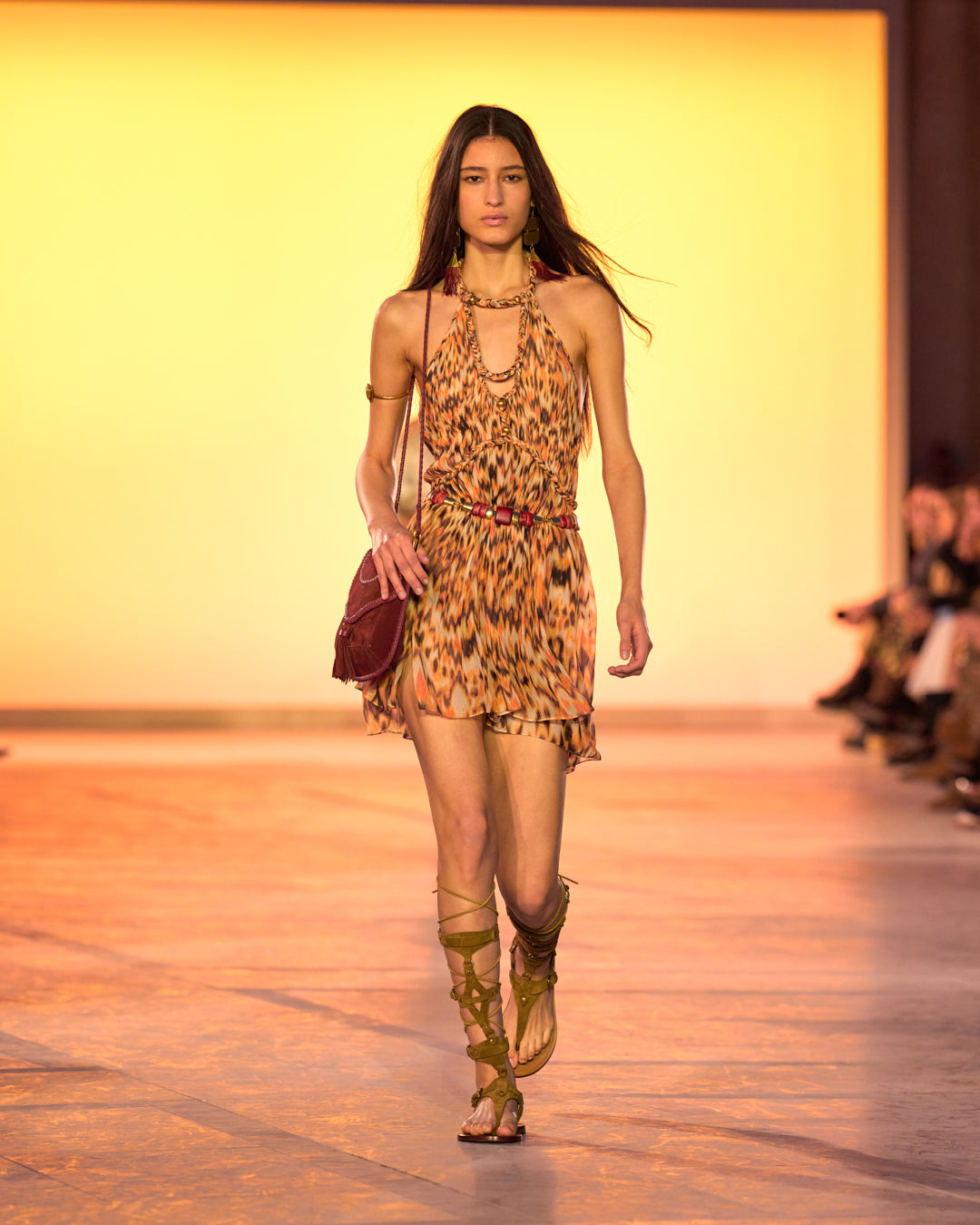 Female model on the catwalk, wearing the Rozilda halter dress in printed gathered silk, the Anahi bag and the Nensi leather sandals.
