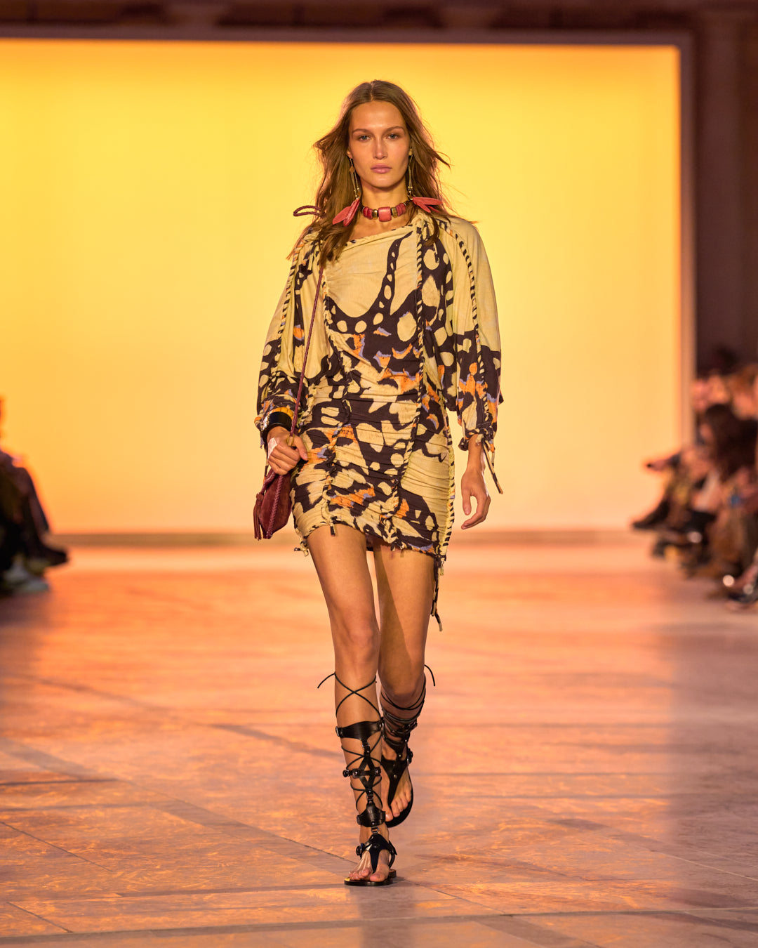 Female model on the catwalk, wearing the Zina dress in woven jersey, the Anahi bag in burgundy and black sandals.