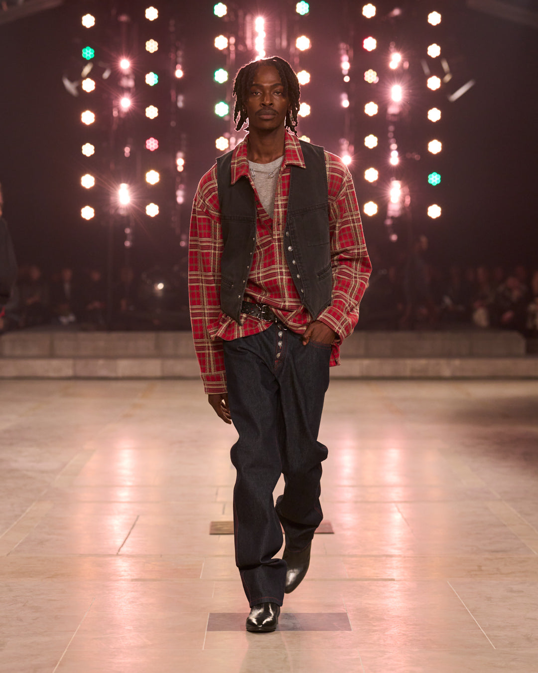 Men walking the FW25 show with checked printed red shirt and black pants.