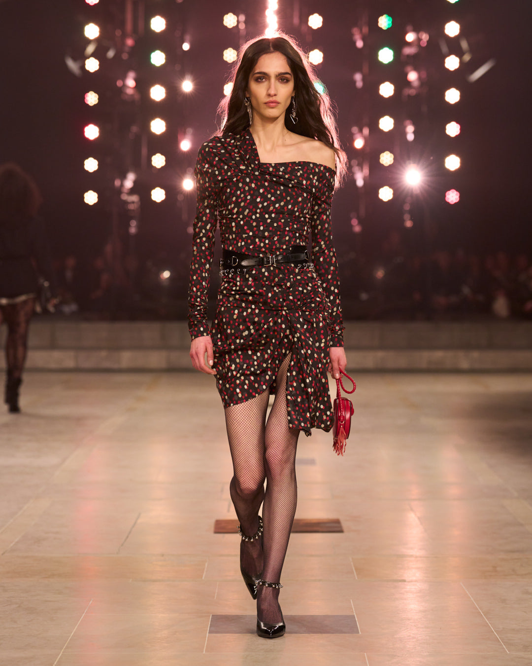 Model walking the FW25 show with polka dots dress unveiling the shoulder.