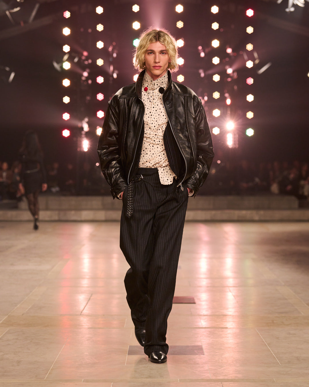Men model walking with leather bomber jacket, polka dotshirt and striped tuxedo large pants.