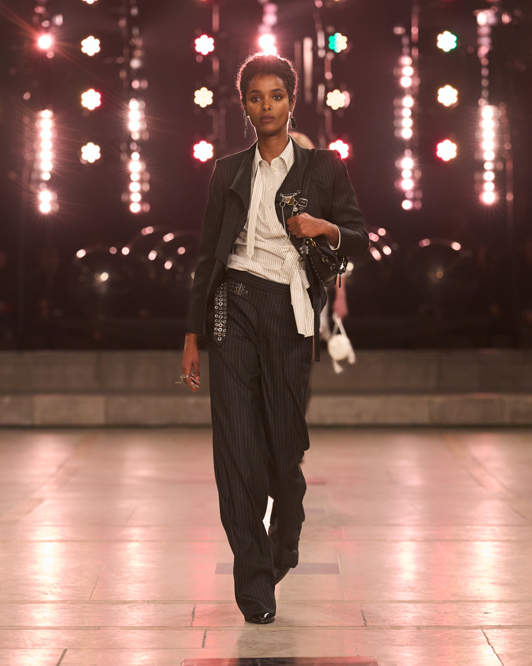 Model wearing striped white shirt and black pant with oskan moon bag.