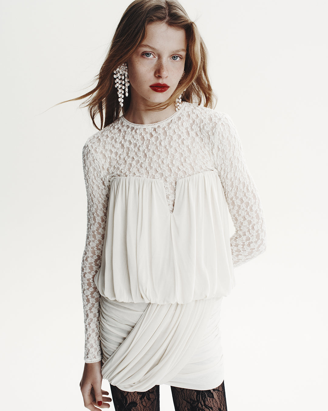 The model is dressed with the Amalia bustier in draped jersey and the Gaelle long-sleeved top in lace with the Hanabi pearl dangle earrings.